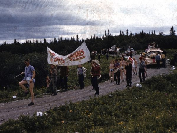 Campers marching down the camp road with a banner and cars made up as floats